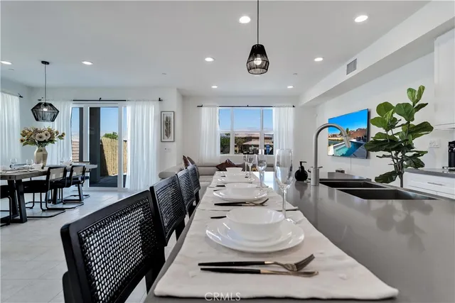 a room with stainless steel appliances a dining table wooden floor and a view of kitchen