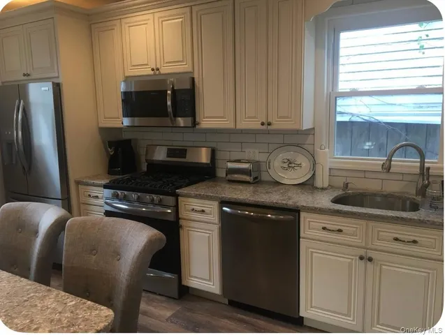 a kitchen with stainless steel appliances granite countertop a sink a stove a microwave a refrigerator and cabinets