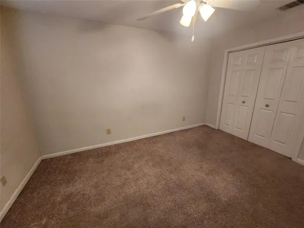 an empty room with a fan & a window