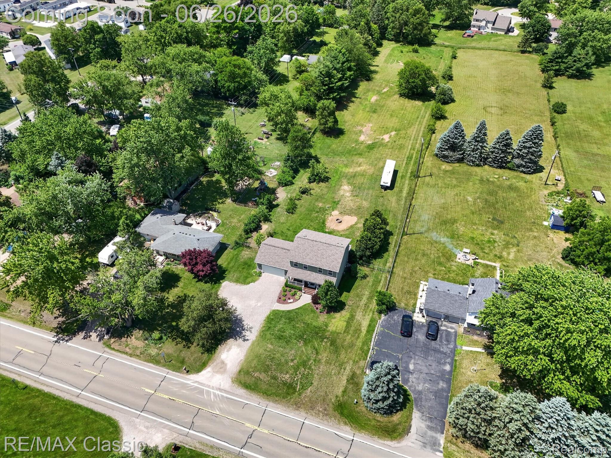 3205 North Milford Road Highland, MI 48357 - Photo 49 of 53 Expansive property featuring a two-story residence with a gray shingle roof, a generously sized lot, abundant mature trees, a long paved driveway, and a large grassy field