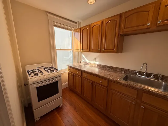 a kitchen with granite countertop a sink stove and cabinets
