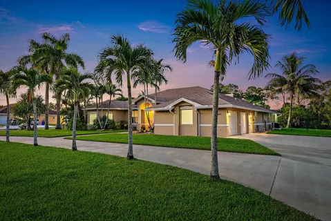 a view of a white house with a big yard and palm trees
