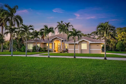 a front view of a house with a yard and palm trees