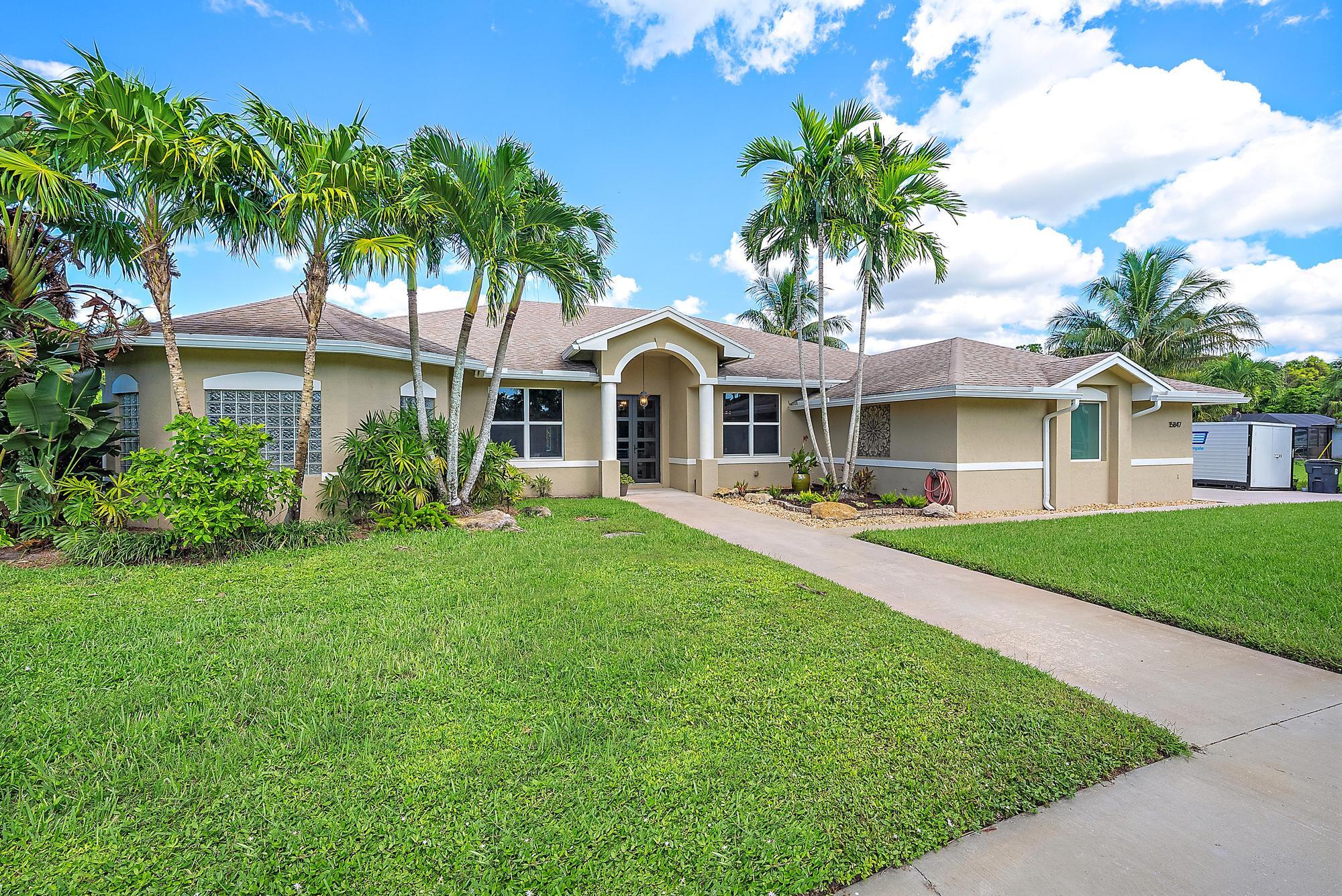15847 86th Road North Loxahatchee, FL 33470 - Photo 30 of 45 a front view of a house with a garden and trees