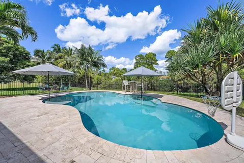 a view of a swimming pool with a table and chairs under an umbrella