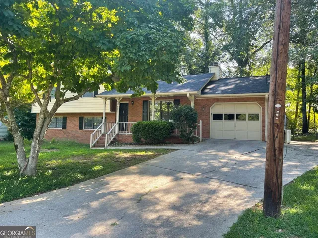 a view of a yard in front of a house with plants and large tree