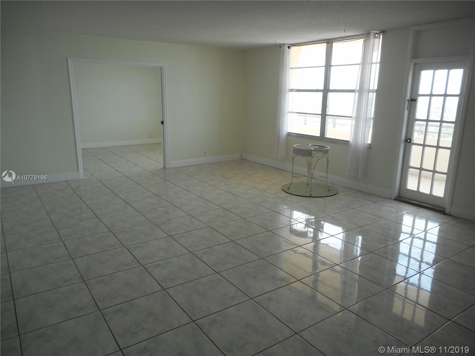 9511 Collins Avenue, Unit 1209 Surfside, FL 33154 - Photo 6 of 20 an empty room with chandelier and windows