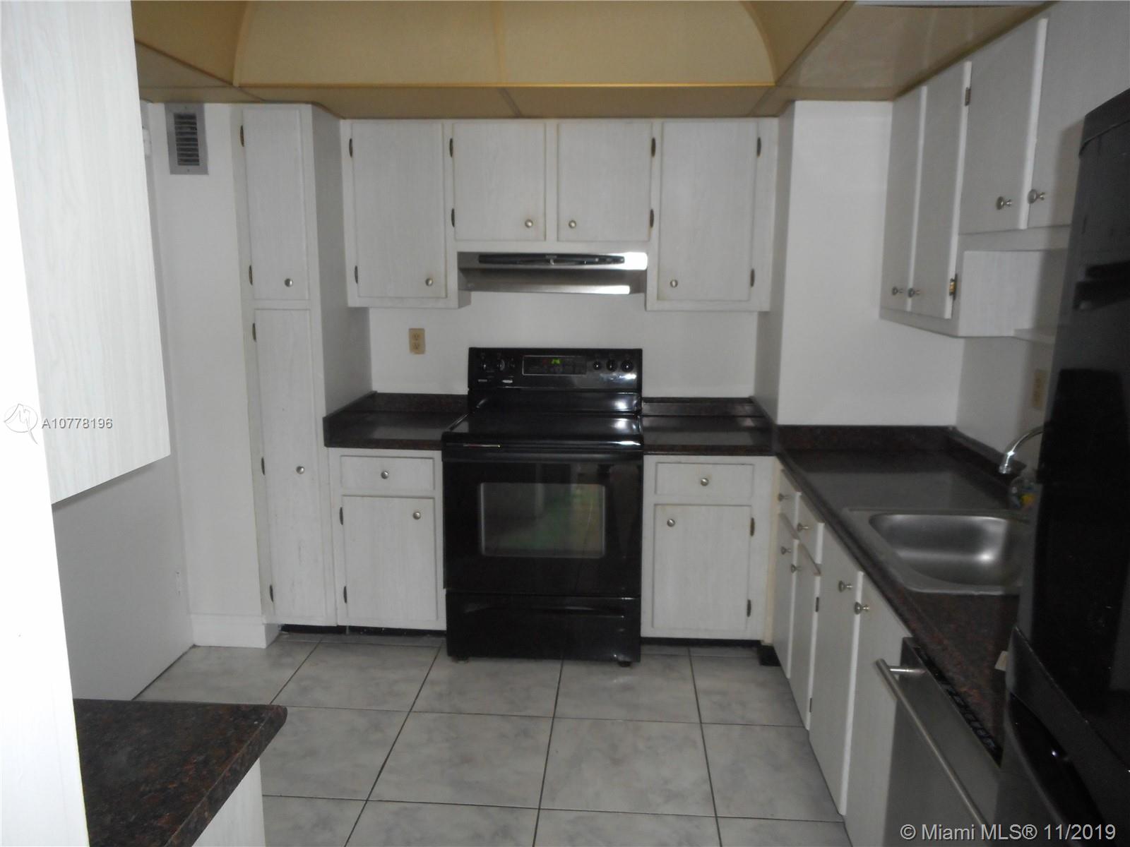9511 Collins Avenue, Unit 1209 Surfside, FL 33154 - Photo 7 of 20 a kitchen with a stove sink and cabinets
