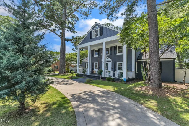 a view of a house with a yard and large tree