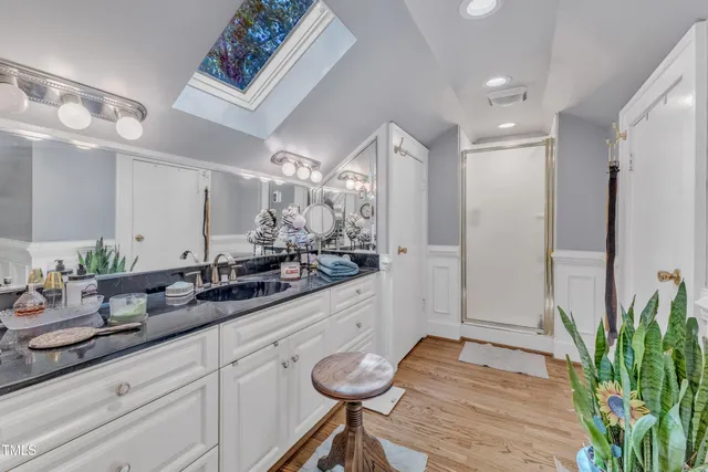 a spacious bedroom with a bed a dresser and wooden floor