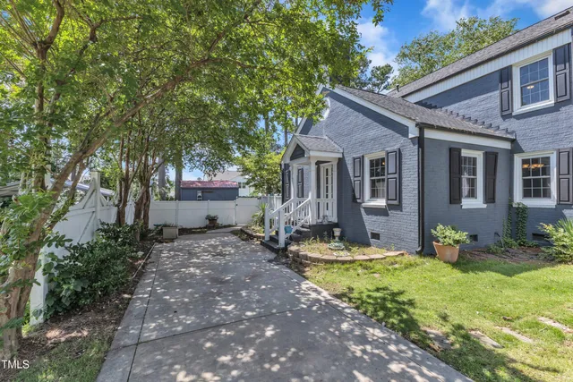 a front view of a house with garden and trees