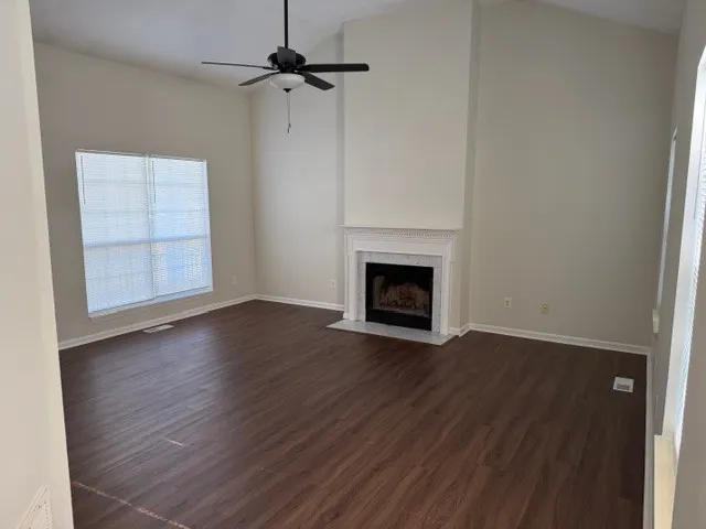 a view of empty room with wooden floor and fireplace
