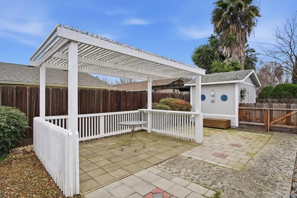a view of a white house with a small yard and wooden fence