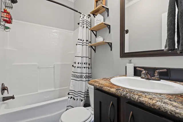 a bathroom with a granite countertop sink a toilet and shower
