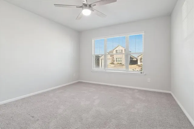 an empty room with a fan & a window