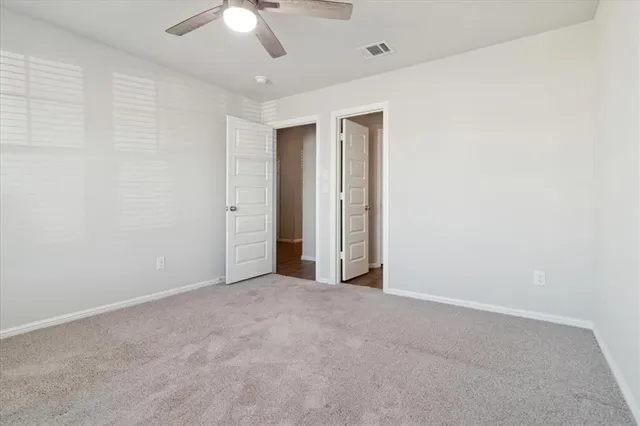 an empty room with a ceiling fan and a window
