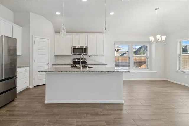 a large kitchen with stainless steel appliances a large counter top a stove a refrigerator and a sink