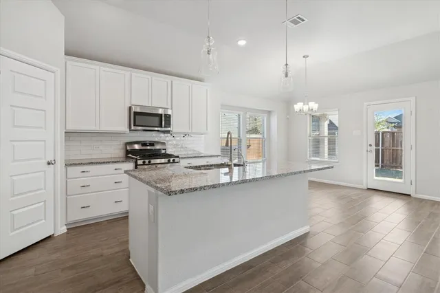 a kitchen with granite countertop a stove a sink and a refrigerator