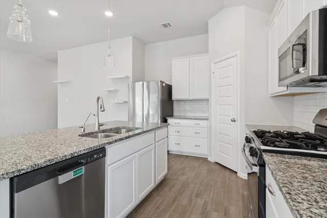 a kitchen with stainless steel appliances kitchen island granite countertop a stove sink and cabinets