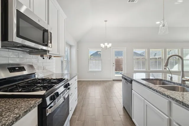 a kitchen with granite countertop a sink stainless steel appliances and cabinets