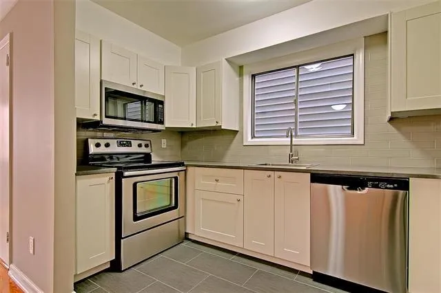 a kitchen with granite countertop white cabinets and stainless steel appliances