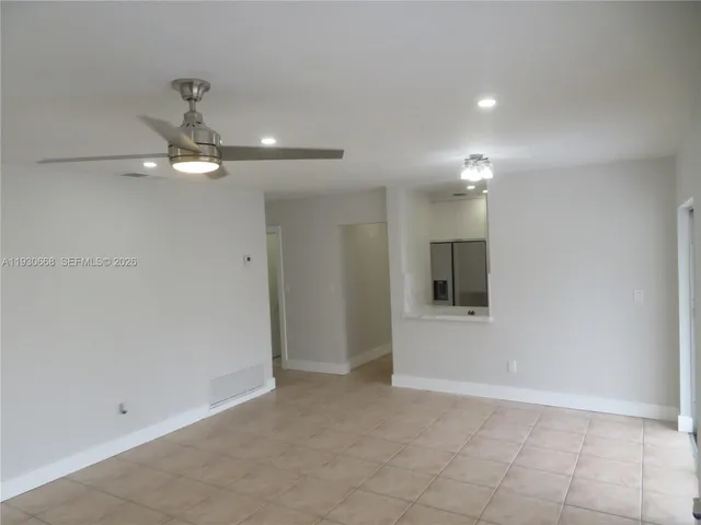a view of a refrigerator in kitchen and an empty room