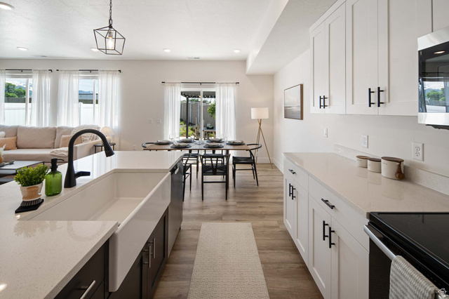 461 West 490 North Lindon, UT 84042 - Photo 5 of 18 Kitchen featuring white cabinetry, dark cabinets, light stone countertops, decorative light fixtures, and appliances with stainless steel finishes