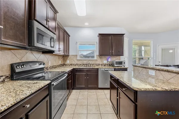 a kitchen with stainless steel appliances granite countertop a sink stove and cabinets