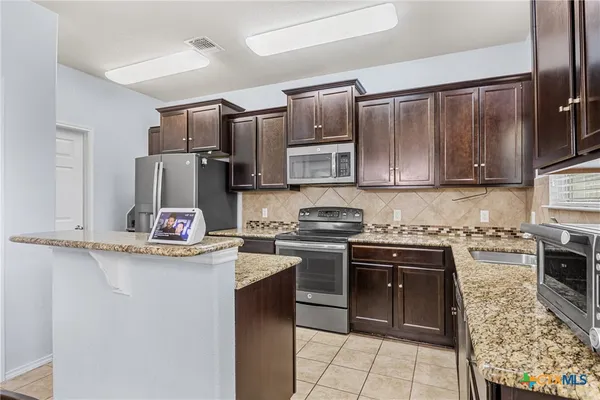 a kitchen with kitchen island granite countertop a stove sink microwave and refrigerator