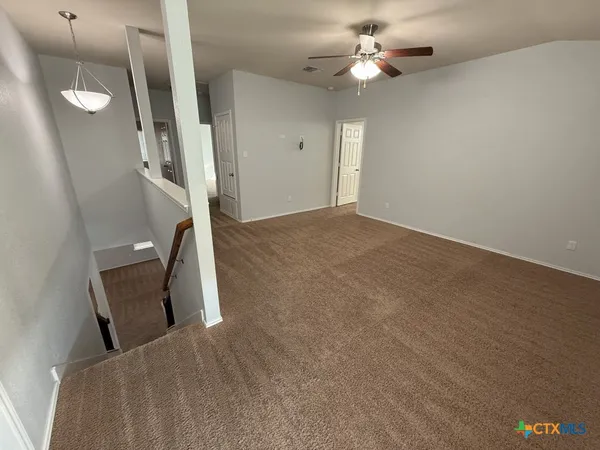 a view of a bedroom with staircase and a ceiling fan