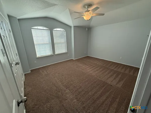 an empty room with windows and fan