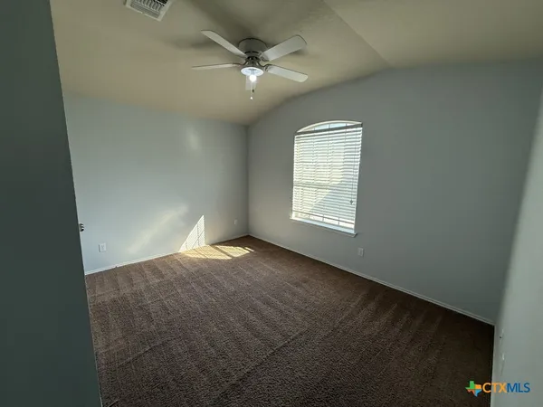 an empty room with windows and fan