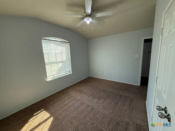 an empty room with windows and fan