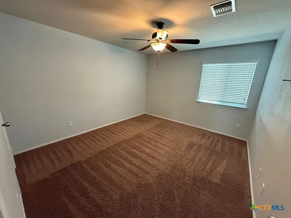 an empty room with a chandelier fan and windows