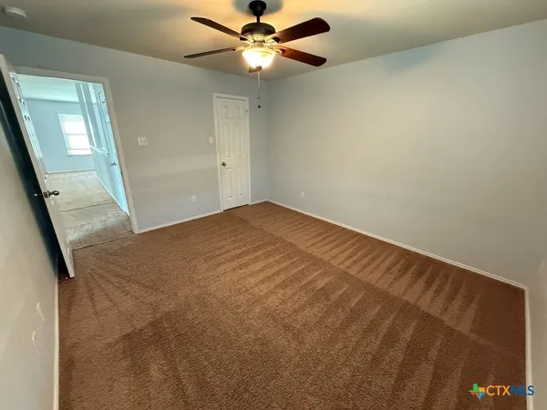 an empty room with windows and fan