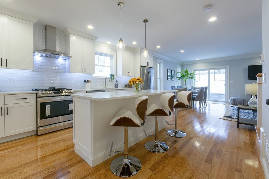 211 West Street, Unit 211 Needham, MA 02494 - Photo 7 of 29 a kitchen with stainless steel appliances granite countertop a stove top oven a sink dishwasher a dining table and chairs with wooden floor