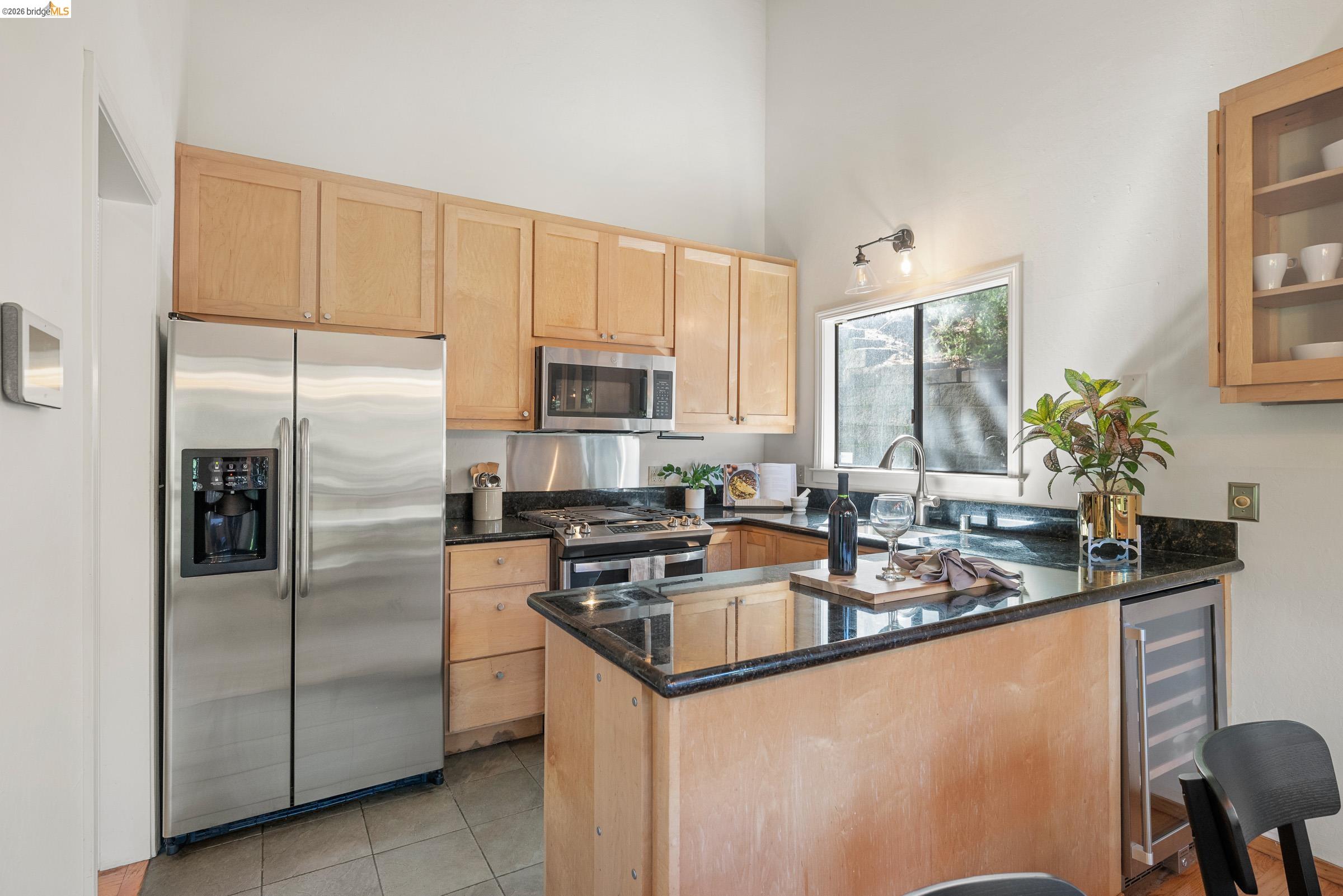 6600 Heather Ridge Way Oakland, CA 94611 - Photo 22 of 66 Kitchen featuring light wood cabinetry, granite countertops, stainless steel appliances, a built-in wine refrigerator, and a window above the sink