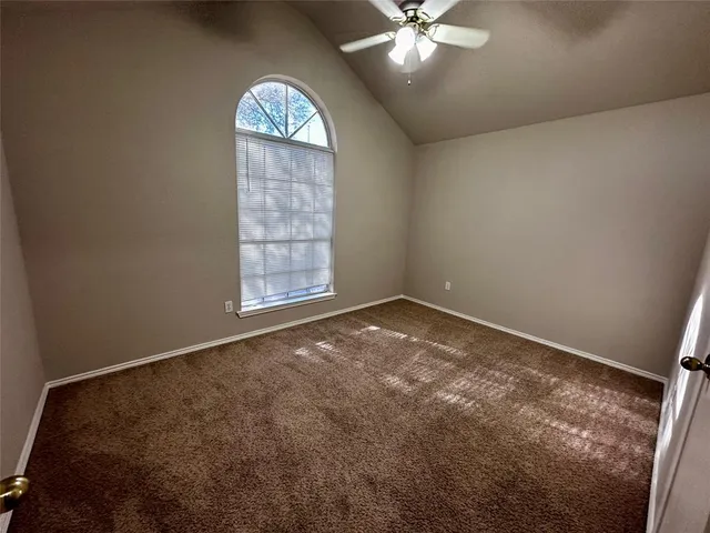 an empty room with windows and chandelier fan