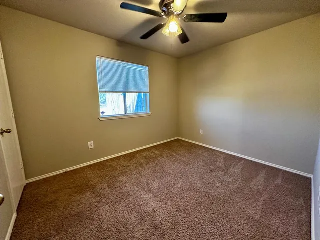 an empty room with a window and a ceiling fan