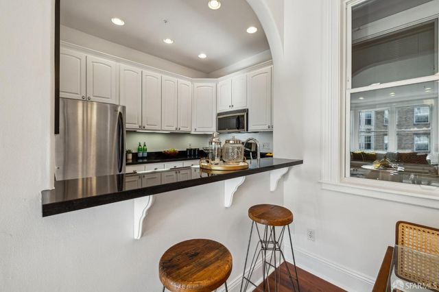 a kitchen with stainless steel appliances granite countertop a refrigerator a stove a sink dishwasher and white cabinets with wooden floor