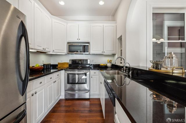 a kitchen with a sink dishwasher a stove top oven a refrigerator and cabinets with wooden floor