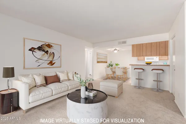 a living room with furniture potted plant and kitchen view