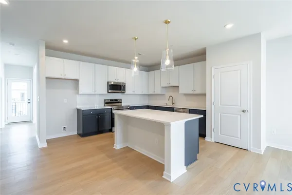 a kitchen with stainless steel appliances granite countertop a stove a sink dishwasher a refrigerator and white cabinets with wooden floor
