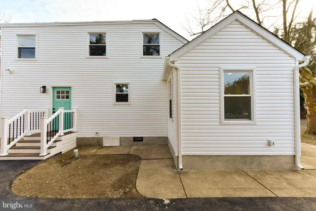 a view of a white house with a yard and lawn chairs