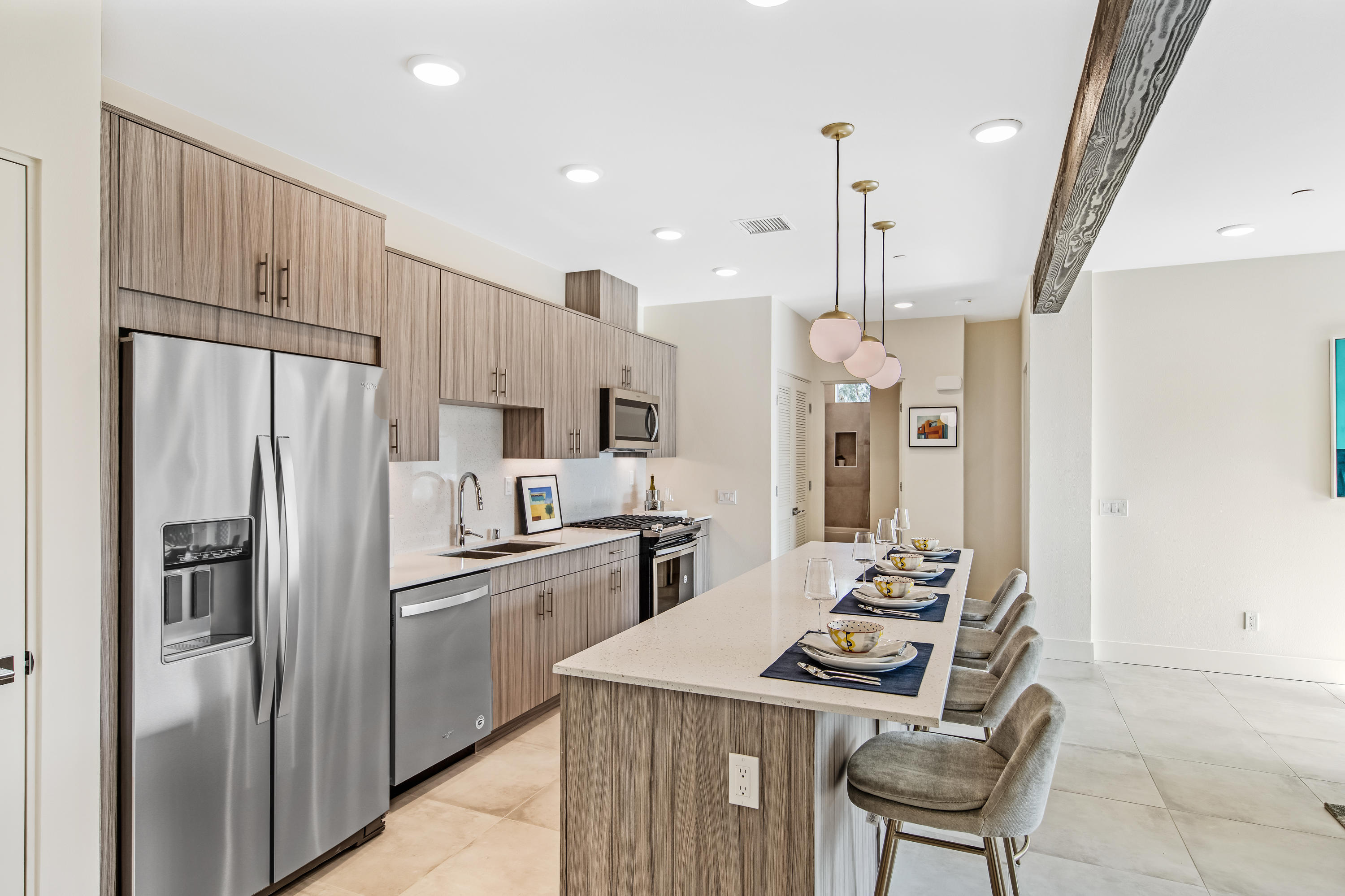 161 The Riv Palm Springs, CA 92262 - Photo 3 of 15 a kitchen with stainless steel appliances kitchen island granite countertop a refrigerator a sink dishwasher a stove and a dining table with wooden floor
