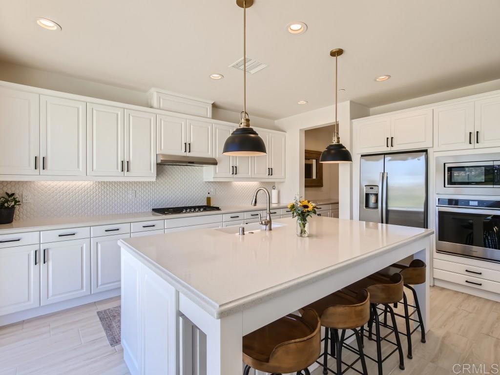 31657 Calle De Las Estrellas Bonsall, CA 92003 - Photo 2 of 24 a kitchen with kitchen island a stove a sink a center island and cabinets