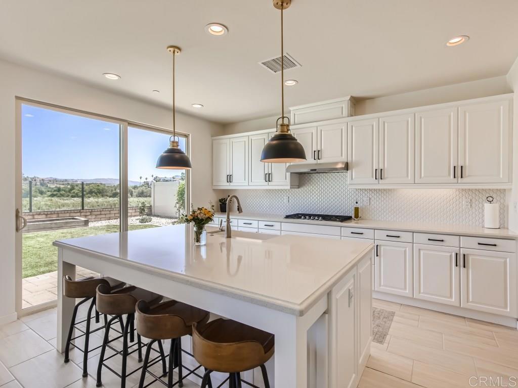 31657 Calle De Las Estrellas Bonsall, CA 92003 - Photo 5 of 24 a kitchen with kitchen island granite countertop a sink a center island and appliances