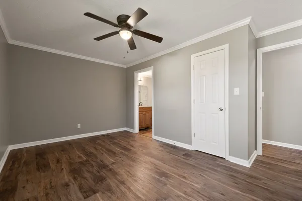 an empty room with wooden floor and ceiling fan
