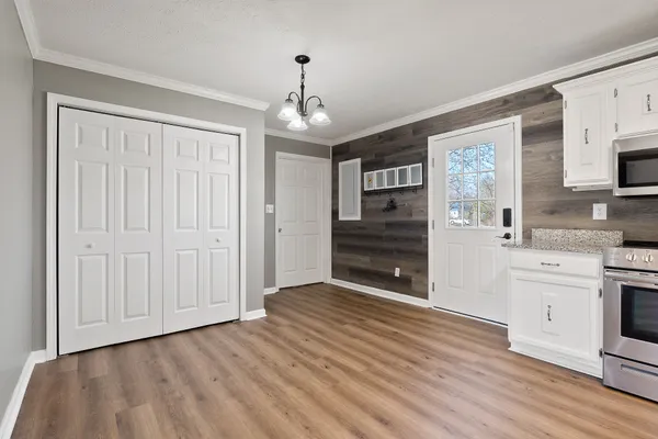 a view of a kitchen with an empty room and wooden floor