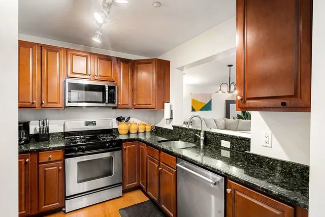 a kitchen with granite countertop a sink stainless steel appliances and cabinets